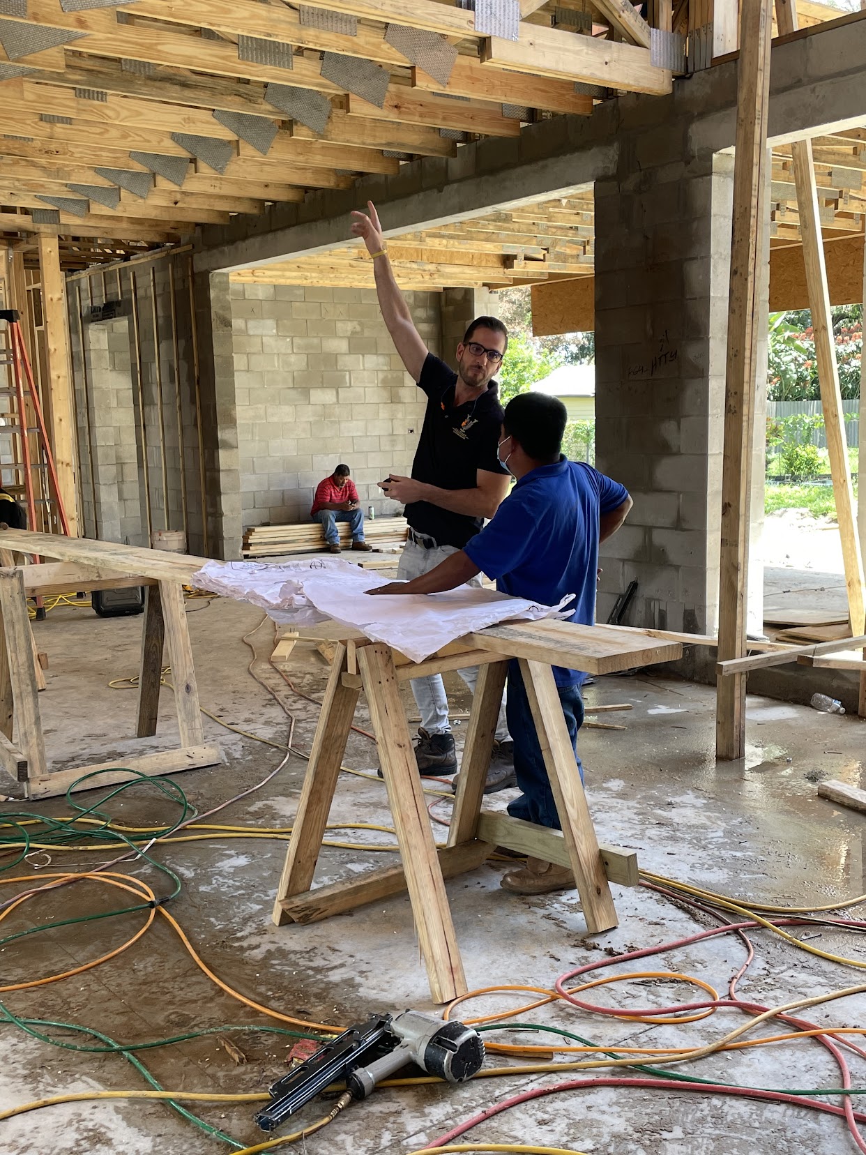Christopher directing crew over blueprints on site